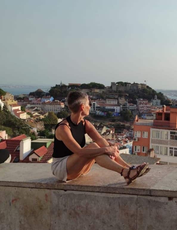 Daniela Bernauer sitzt auf einer Mauer und blickt über die Dächer von Lissabon. Sie ist das Herz von KinderLiebe.